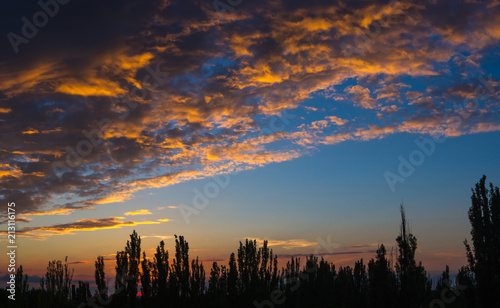 Landscape with dramatic light - beautiful golden sunset with saturated sky and clouds.