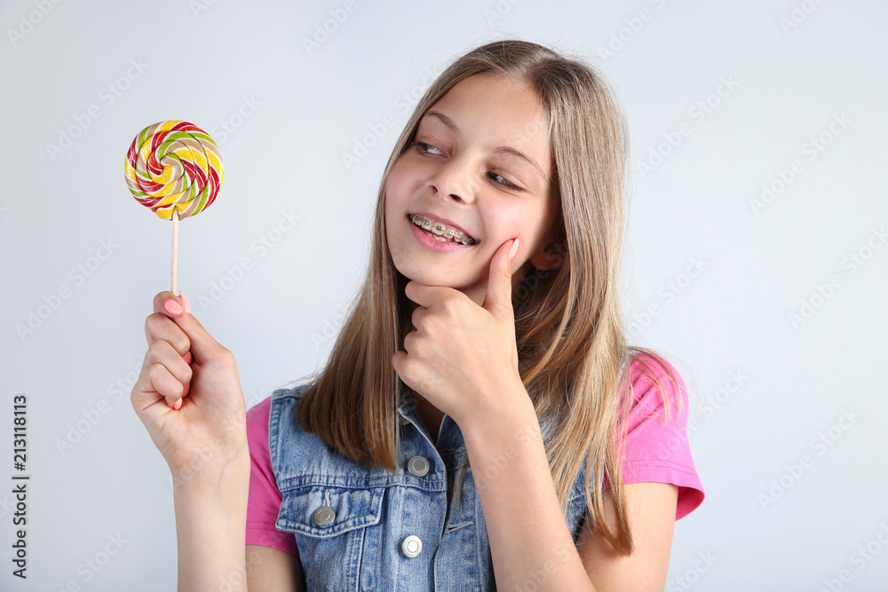 Young girl with lollipop on grey background