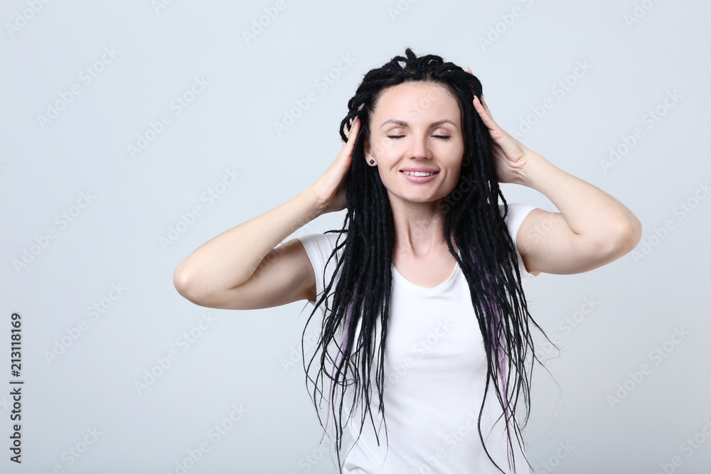 Fototapeta premium Cute young woman with dreadlocks on grey background