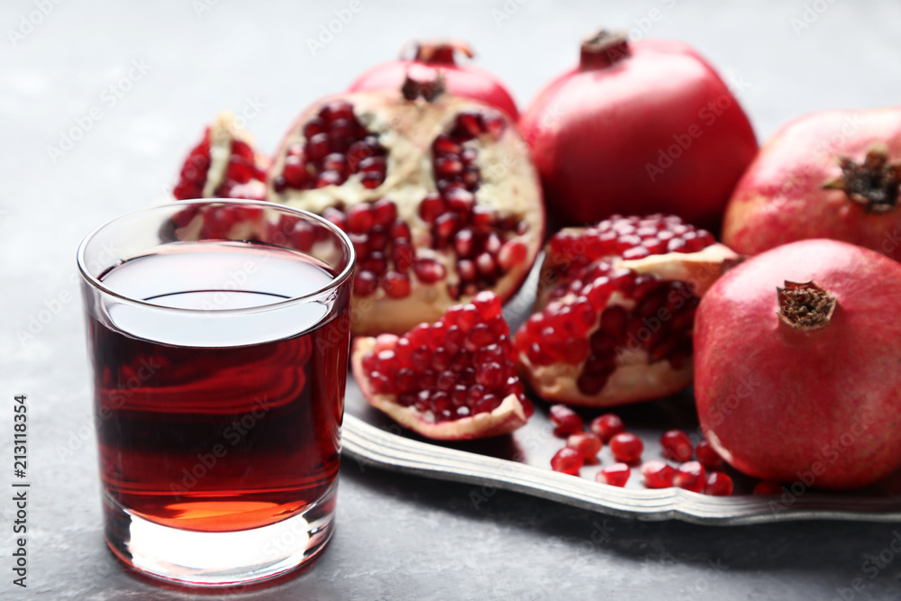 Pomegranate fruit and juice in glass on grey wooden table Pomegranate fruit and juice in glass on grey wooden table