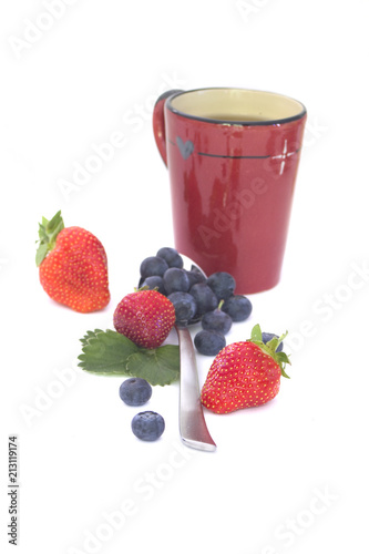 Fruit tea   strawberries and blueberries with a red mug isolated on white
