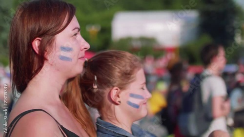 Side view of girls who watch football match supporting Argentina in fan zone