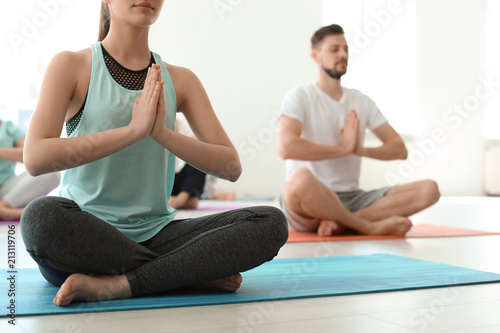 Group of people in sportswear practicing yoga indoors