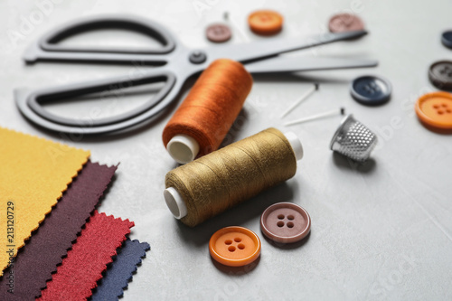 Set of tailoring accessories and fabric on light background