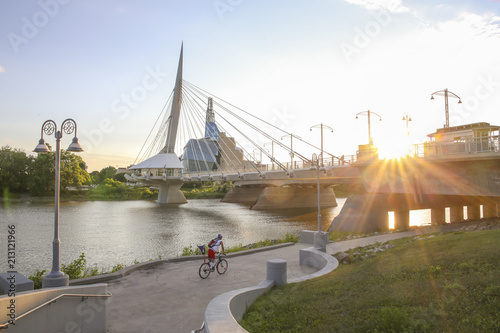 Cyclists along Red River in a sunny day. Peaceful sunset scene. Winnipeg, Canada.