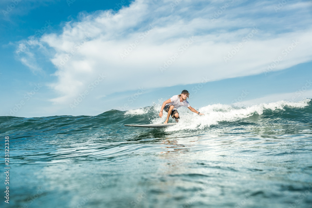 distant view of male surfer riding waves in ocean at Nusa Dua Beach, Bali, Indonesia distant view of male surfer riding waves in ocean at Nusa Dua Beach, Bali, Indonesia