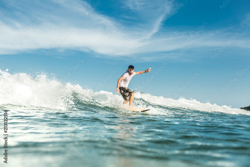 young male surfer riding waves in ocean at Nusa Dua Beach, Bali, Indonesia