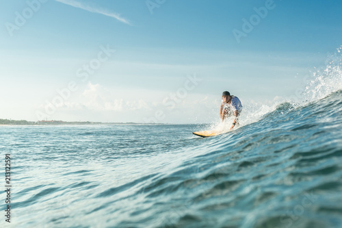 selective focus of male surfer riding on board in ocean at Nusa Dua Beach, Bali, Indonesia © LIGHTFIELD STUDIOS