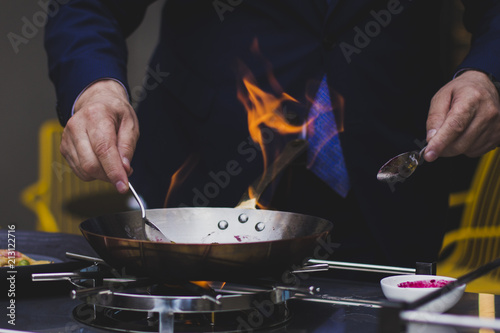 Chef doing flambe to food in pan with alcohol in big flame