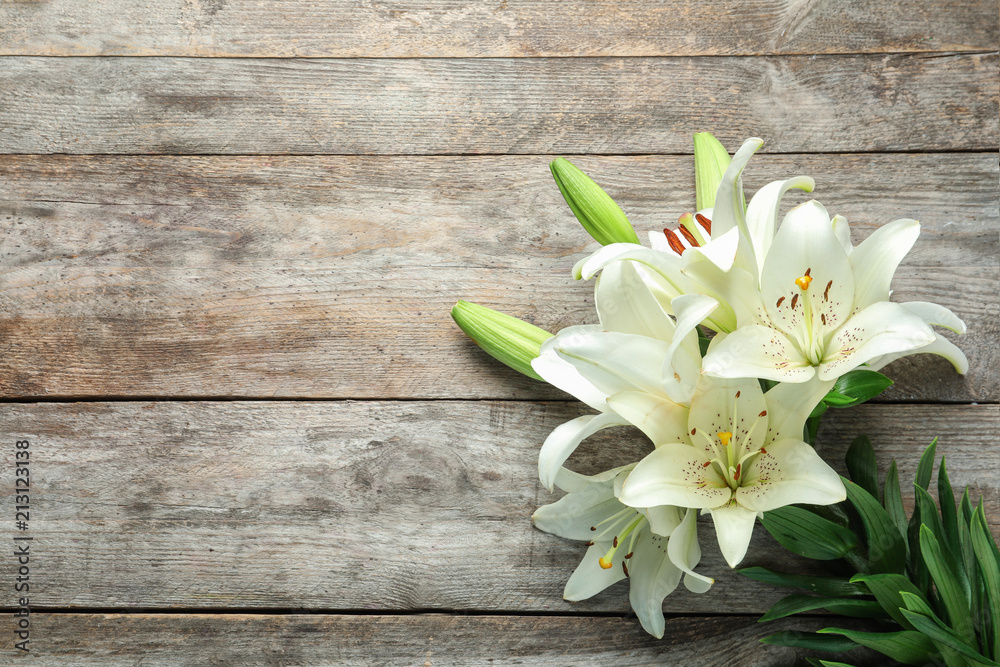 Fototapeta premium Płaska kompozycja świeckich z pięknymi kwitnącymi kwiatami lilii na drewnianym tle