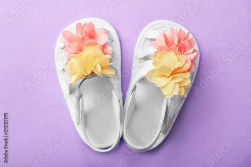Pair of cute baby sandals on color background, top view