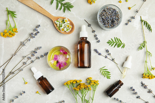 Flat lay composition with essential oils and flowers on light background photo