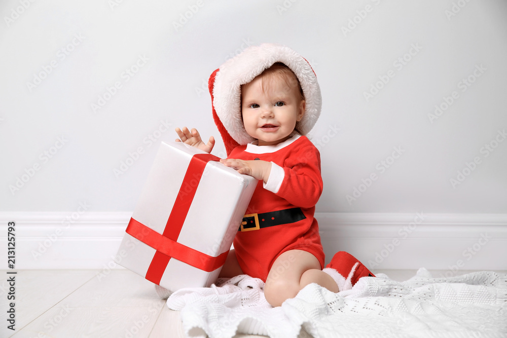 Cute little baby in Christmas costume with gift at home Cute little baby in Christmas costume with gift at home
