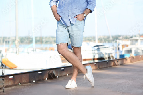 Young hipster man in jean shorts on pier