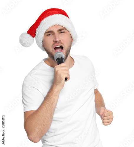Young man in Santa hat singing into microphone on white background. Christmas music
