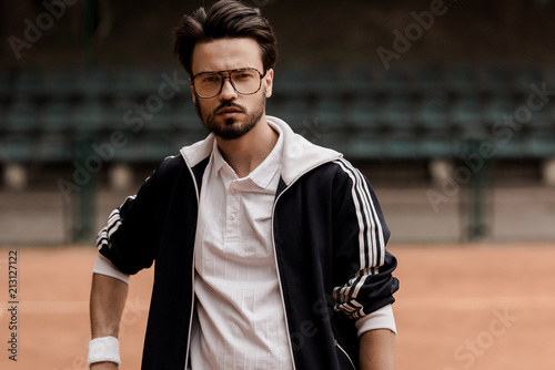 portrait of handsome tennis player looking at camera at tennis court