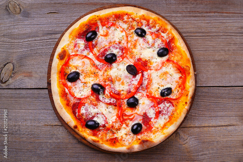 Delicious traditional pizza with ham and black olives on wood  flat lay. Italian food  restaurant menu photo