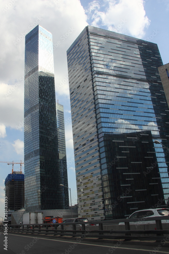 View from road of the glass skyscrapers in Moscow - business center Moscow city in the afternoon against the blue sky with clouds View from road of the glass skyscrapers in Moscow - business center Moscow city in the afternoon against the blue sky with clouds