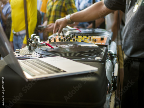 close up dj hand playing music using turntable setup and laptop