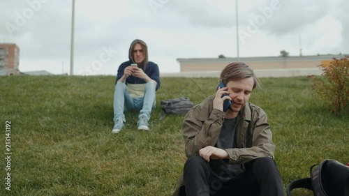 Close up of a young man enjoying talking on a mobile phone in park grass field tourist student. photo