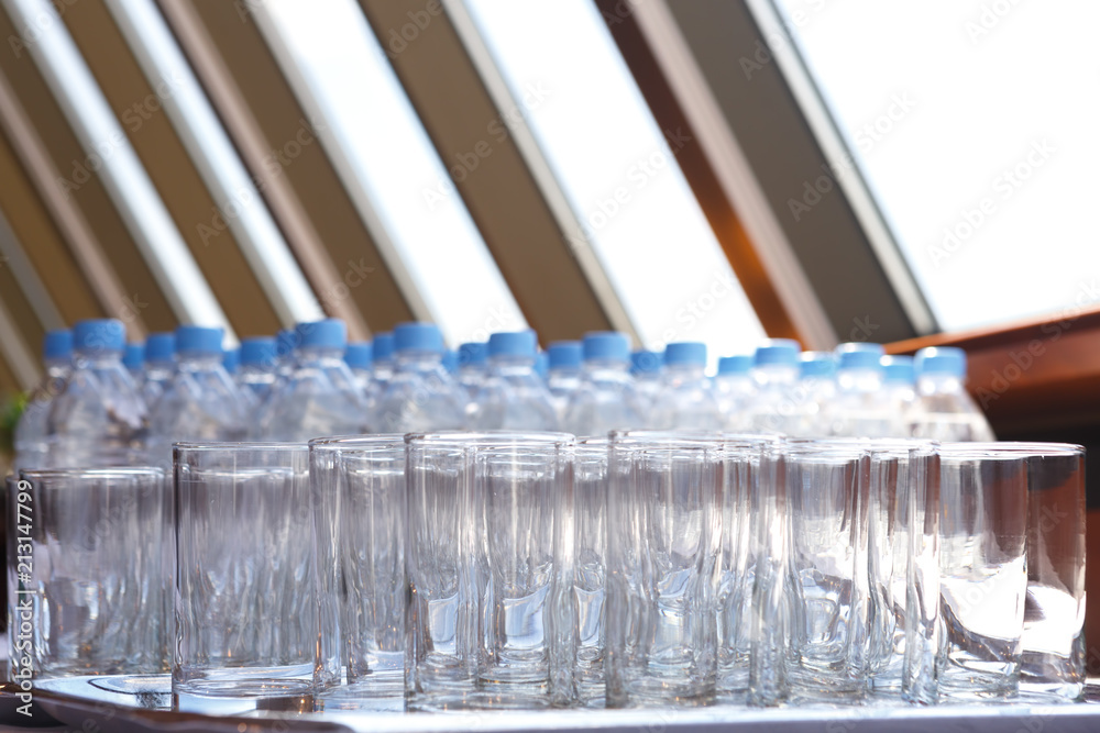 Rows of empty glasses on the background of water bottles Rows of empty glasses on the background of water bottles