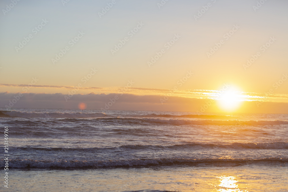 Sunset on coast. Medium waves. Sun in low right corner. Lens flares.