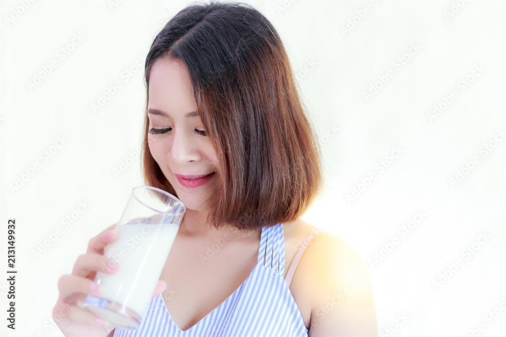 Health concept: Charming beautiful girl loves to drink milk for good health that makes her strong. Attractive woman holds a glass of milk. A gorgeous girl looks happy, Isolated and white background Health concept: Charming beautiful girl loves to drink milk for good health that makes her strong. Attractive woman holds a glass of milk. A gorgeous girl looks happy, Isolated and white background