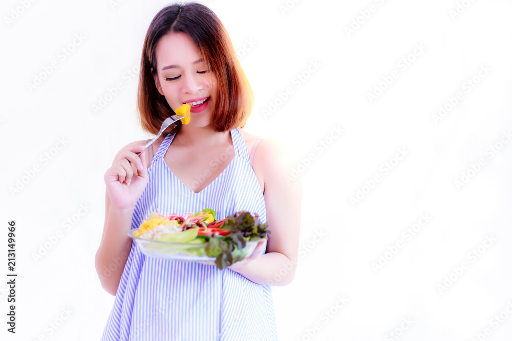 Health concept: Beautiful pregnant woman is eating vegetable by using fork. Gorgeous mother has enjoyed or happiness salad. It is good for health and baby or fetus, isolated on white and copy space. Health concept: Beautiful pregnant woman is eating vegetable by using fork. Gorgeous mother has enjoyed or happiness salad. It is good for health and baby or fetus, isolated on white and copy space.