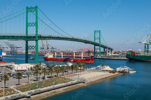 Red Bulk Carrier Ship Passing Under the Vincent Thomas Bridge and Container Ships Unloading in Los Angeles Long Beach California Shipping Port