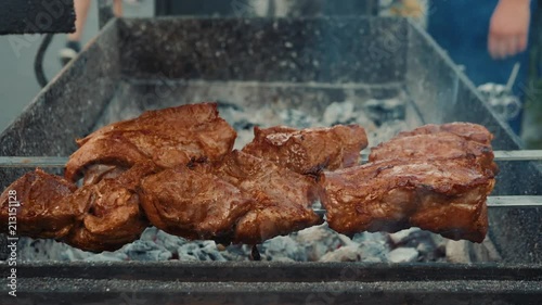 Two hands turning skewers with pieces of juicy fragrant steaming meat over a hot fuming brazier. Homemade. Street food. photo