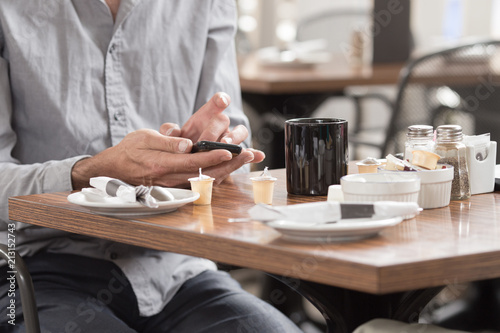 A man using a smart phone while enjoying a cup of coffe in a cafe