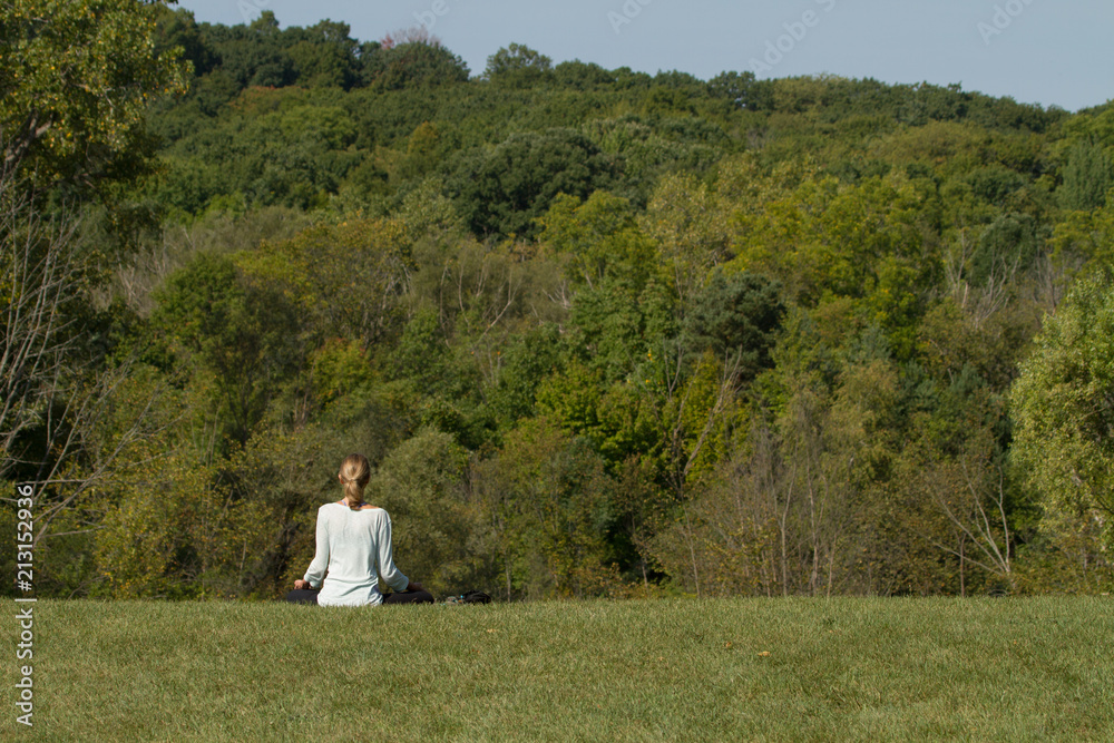 A woman practicing yoga or meditation in a park A woman practicing yoga or meditation in a park