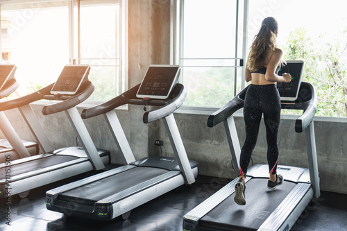 Cute young woman exercising on treadmill at a gym.Active young woman running on treadmill. smile and funny emotion.