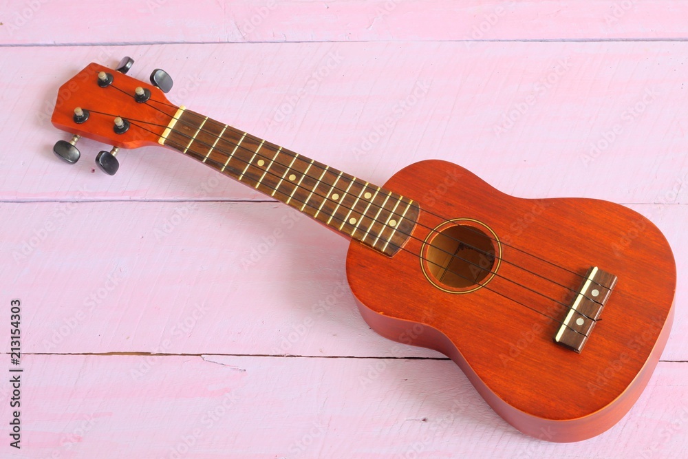 Fototapeta premium A ukulele on the pink wood background.