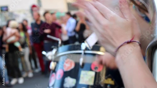 woman applauding the beat with blurry drummer and audience in the background photo
