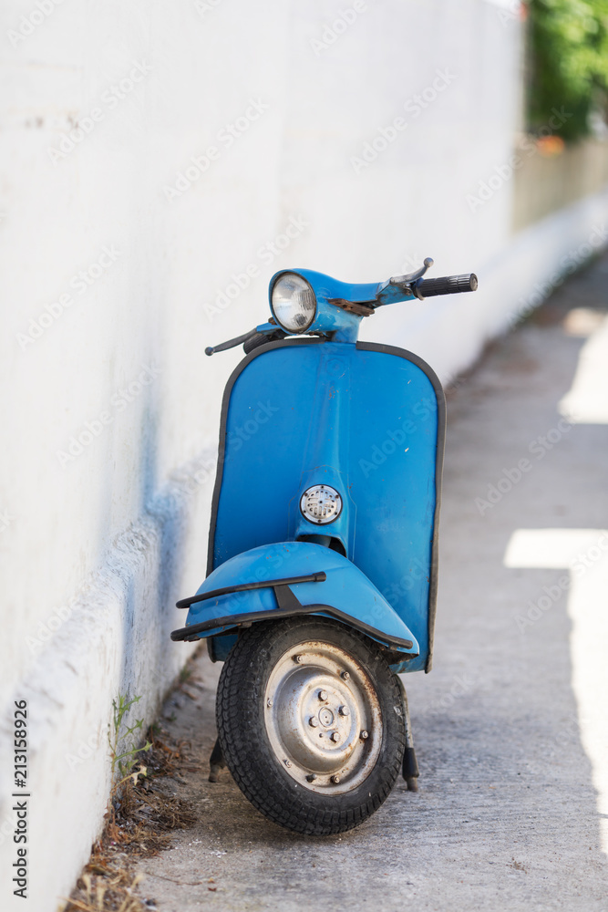 Blue retro scooter next to a while wall