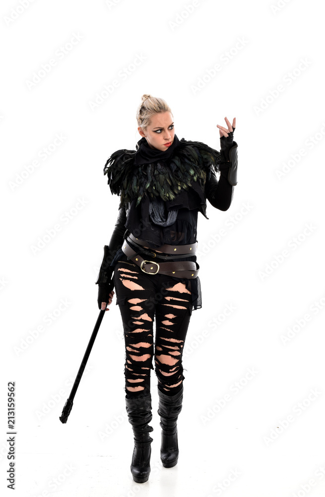 full length portrait of blonde girl wearing black gothic outfit, holding a staff. standing pose, isolated on white studio background. full length portrait of blonde girl wearing black gothic outfit, holding a staff. standing pose, isolated on white studio background.