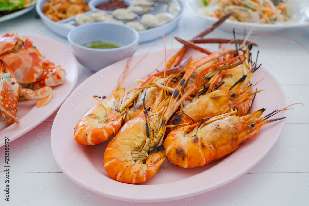 grilled shrimp on dish with spicy seafood saucebrown wooden table background.. grilled shrimp on dish with spicy seafood saucebrown wooden table background..
