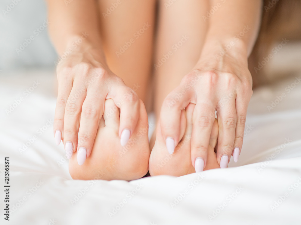 Young woman massaging her foot on the bed., Healthcare concept