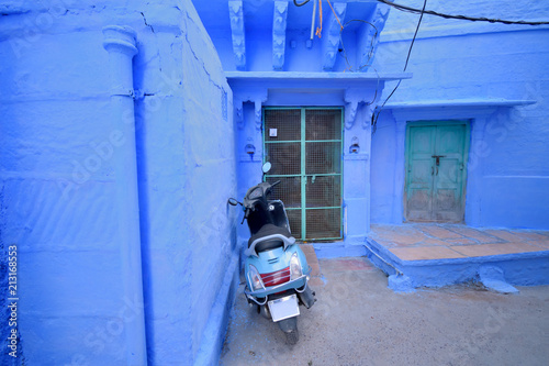 Fototapeta Naklejka Na Ścianę i Meble -  A scooter parked in front of a blue colored house in Jodhpur.