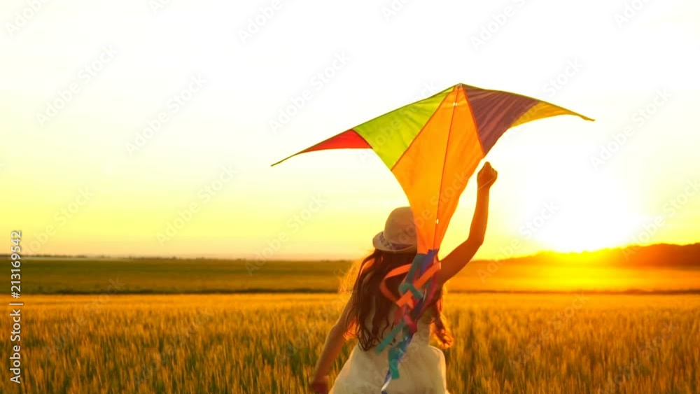 girl running around with a kite on the field.