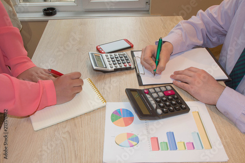 Two business people accountants counting on calculator income for tax form completion hands