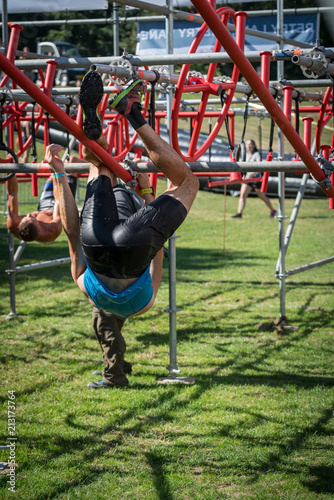 Athlete climbing along a low hanging rig obstacle at an obstacle course race