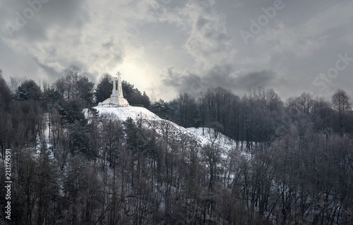 View to the white Three Crosses - a prominent monument in Vilnius, Lithuania, on the Hill of Three Crosses, originally known as the Bald Hill, under dramatic cloudy winter sky.