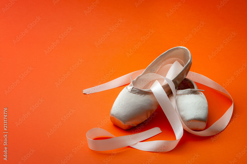 Naklejka premium Ballet dancing concept with a pair of silk shoes isolated on minimalist bright orange background