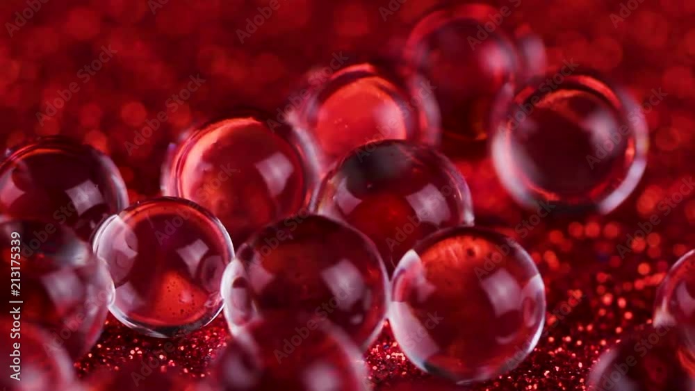 Crystal Gel water balls on red glitter texture rotation. Close up macro footage. Crystal Gel water balls on red glitter texture rotation. Close up macro footage.