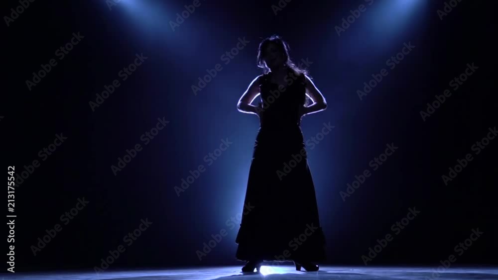 Girl is dancing in a dark room with graceful hand movements. Llight from behind. Smoke background. Silhouette. Slow motion Girl is dancing in a dark room with graceful hand movements. Llight from behind. Smoke background. Silhouette. Slow motion
