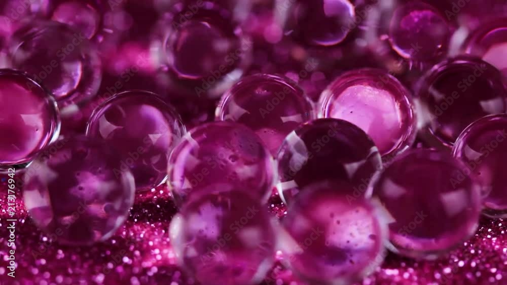 Crystal Gel water balls on pink glitter texture rotation. Close up macro footage. Crystal Gel water balls on pink glitter texture rotation. Close up macro footage.
