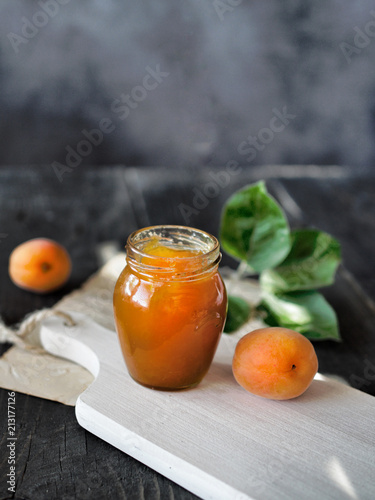 Fresh apricots and apricot jam in jar on rustic wooden table. Copy space.