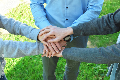 Stack of family people hands on green grass background outdoors. Family business and unity concept.